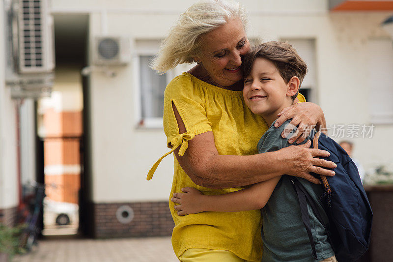 小男孩拥抱着他的奶奶，跟她说再见。他准备去上学。