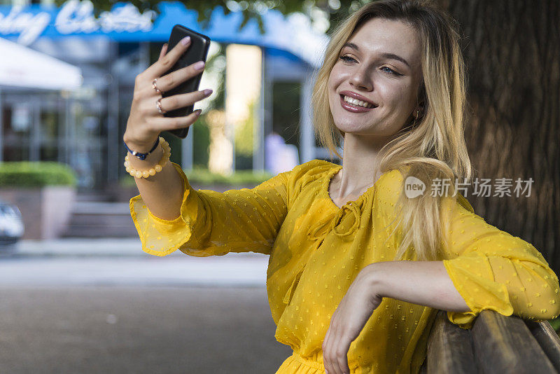 在公园里用手机的女人，在户外微笑的女孩