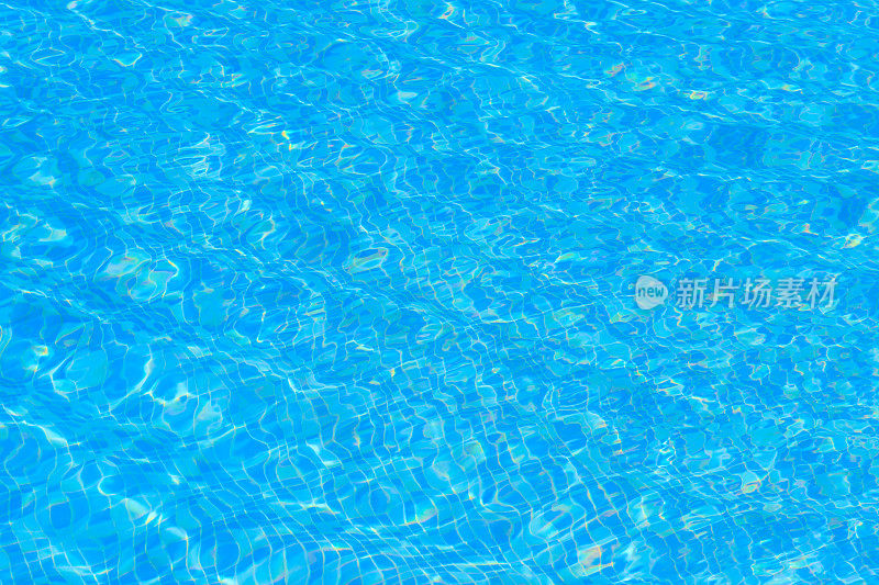 以游泳池水的纹理为背景。蓝色游泳池的表面