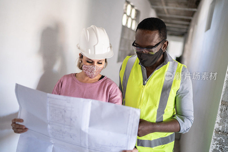 工程师和建筑工人拿着图纸讨论施工——戴着防护口罩