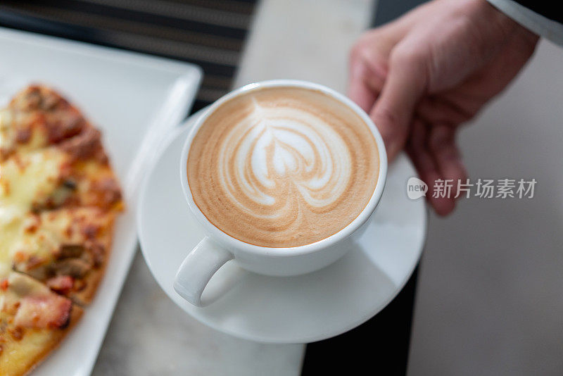 服务员端上美味的咖啡给客人，咖啡上有一颗心型图案
