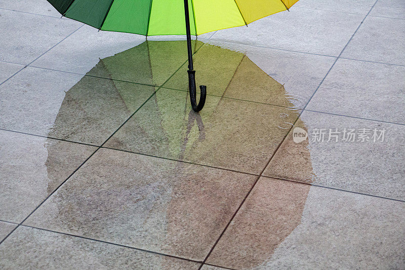 雨点落在彩虹伞上，天以自然为背景