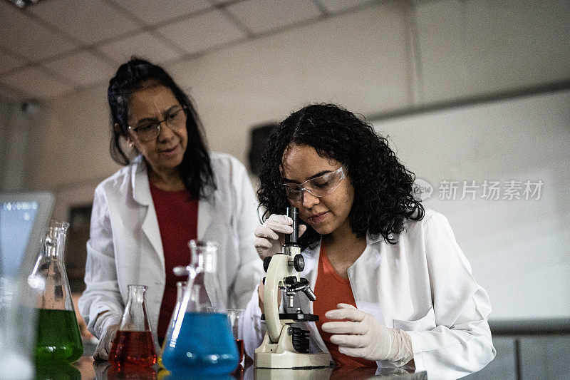 老师在课堂上帮助学生使用显微镜