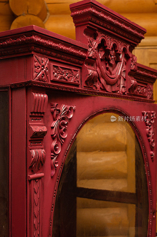 近距离拍摄的古老复兴的橱柜与手工绘制的装饰在红色木制房子的墙壁背景。自行修复家中的古董家具