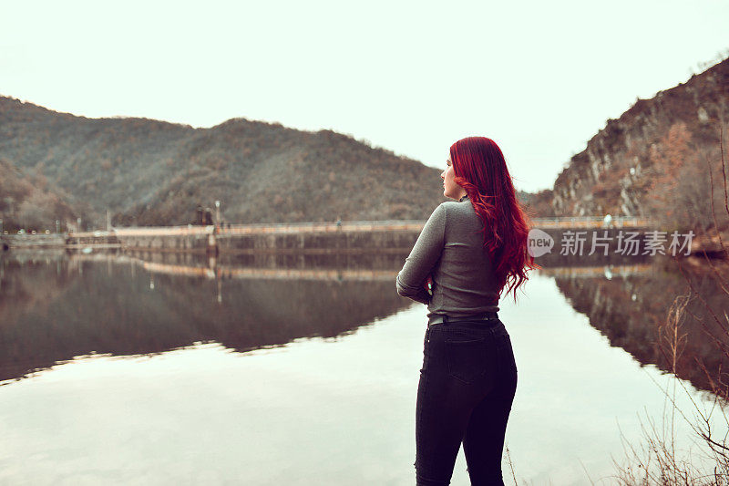 可爱的红发女性在湖上放松时展望未来