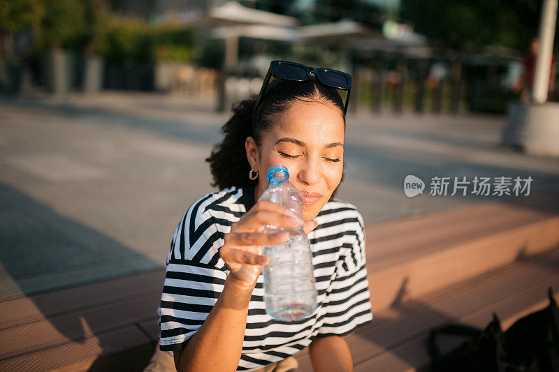 快乐的年轻成年女性喝瓶装水