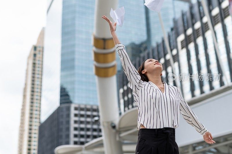 亚洲年轻漂亮的女商人在商业区把一堆文件纸扔向空中