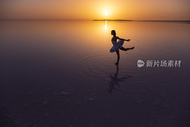 日落时分，芭蕾舞者在图兹湖上跳舞，她在水中的倒影