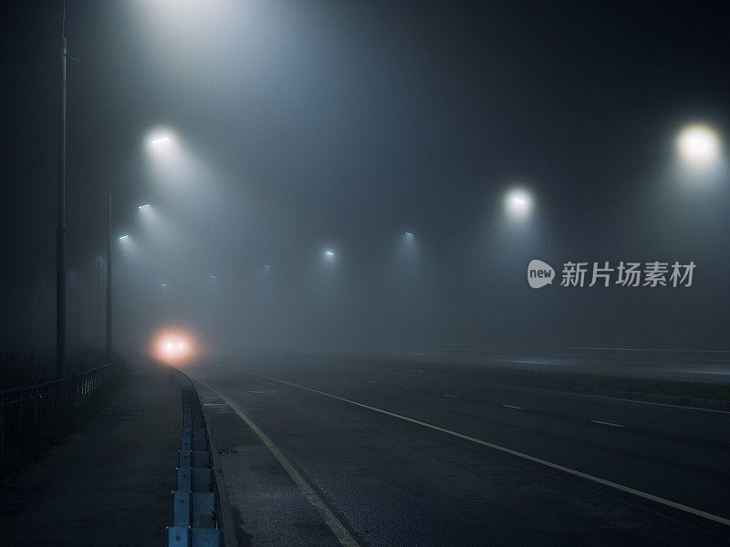 雾蒙蒙的道路。路灯照亮的夜间高速公路