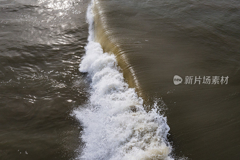 正上方的波浪在肮脏的棕色污染海水中破碎