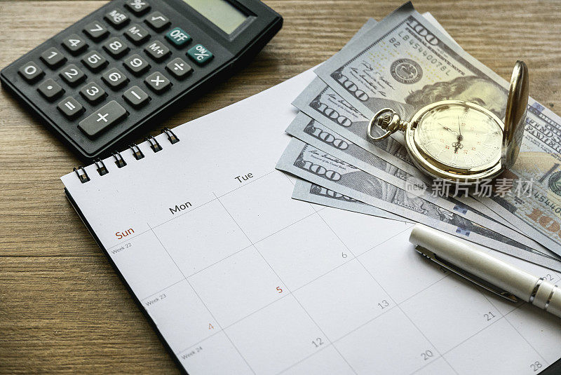 省税省钱和财务规划的概念。计算每月开支。融资债务催收截止日期。木桌上放着钱、日历、时钟和计算器。