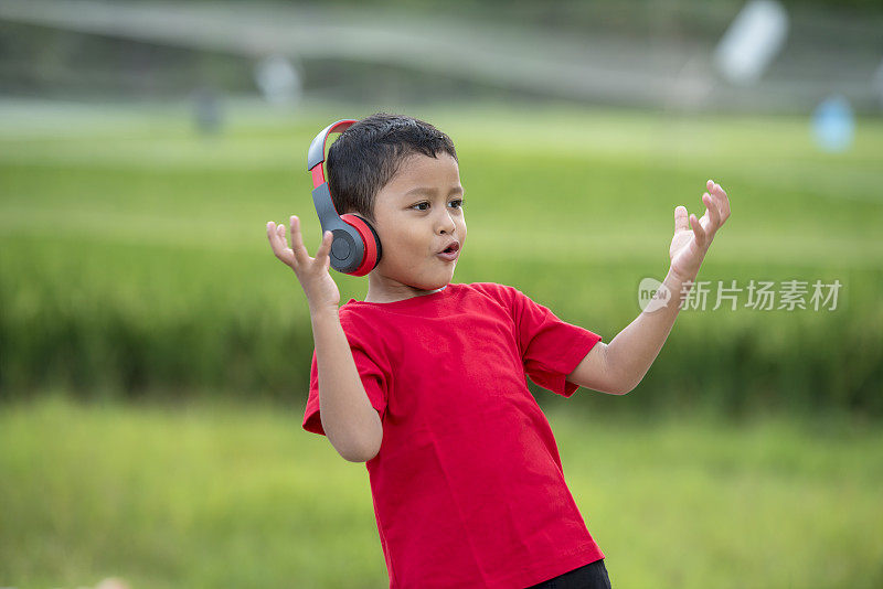 蹒跚学步的男孩用耳机听音乐