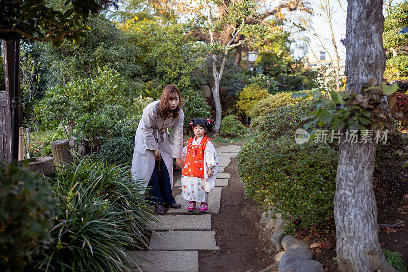 母亲和小女儿穿着和服为七山站在花园的房子里