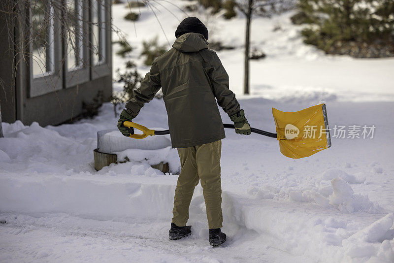 男孩在家里铲雪