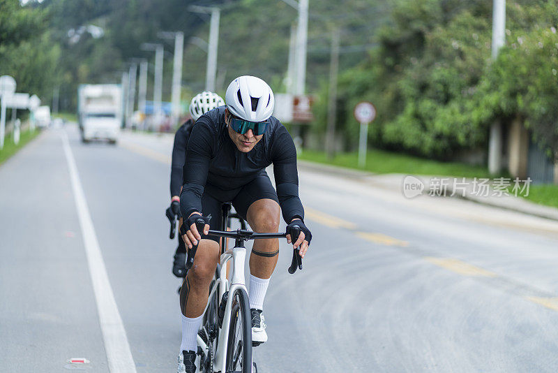这对夫妇戴着安全帽和自行车眼镜，骑着白色自行车行驶在卡西卡-昆迪纳马卡的道路上