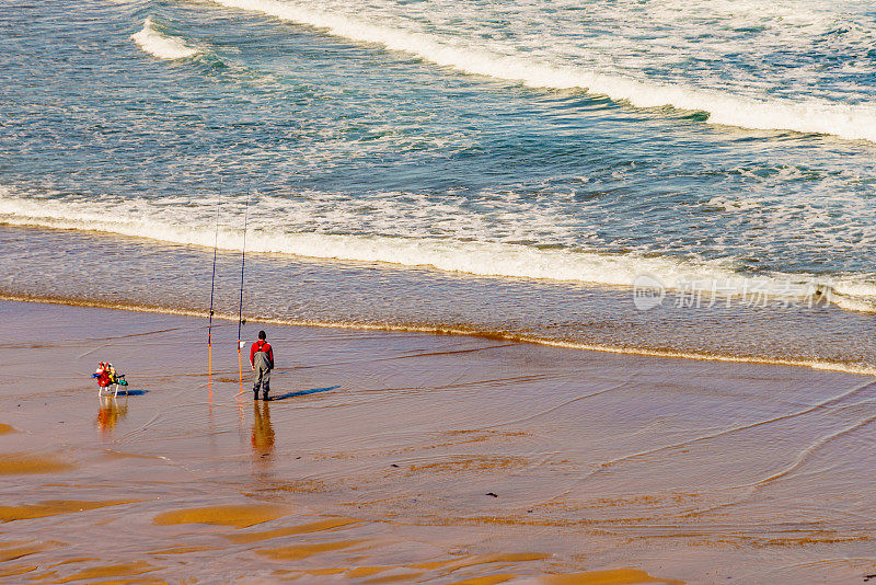 在海边拿着鱼竿的垂钓者