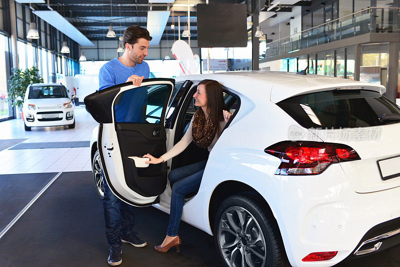 一对年轻夫妇在一家汽车经销商的展厅里购买和测试汽车