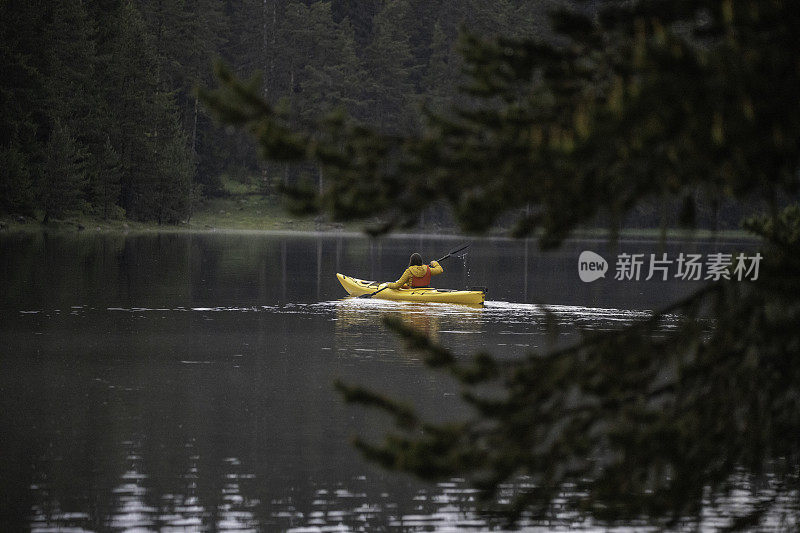 人与自然。女子在山上的湖上划船。