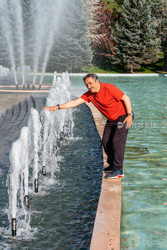 活跃的老朋友在公园度过美好的一天。
接触水。喷泉。