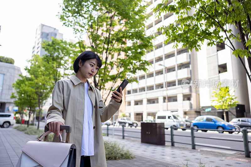 年轻的女商人在城市里使用智能手机