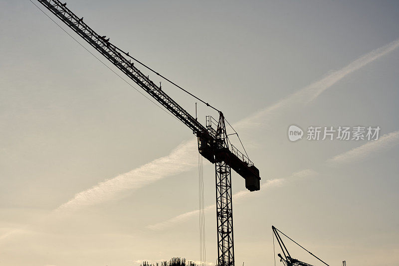 工业建筑起重机和建筑物的剪影在日出的太阳。