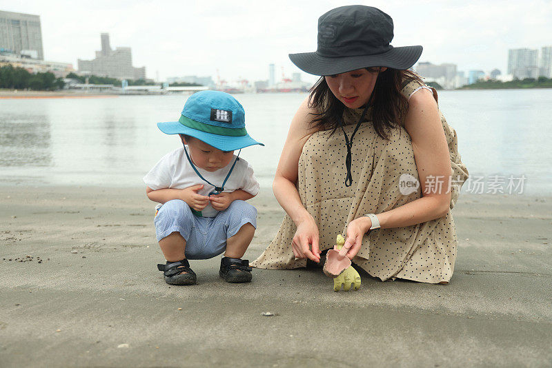 年轻的母亲和她的小儿子在海滩上玩耍