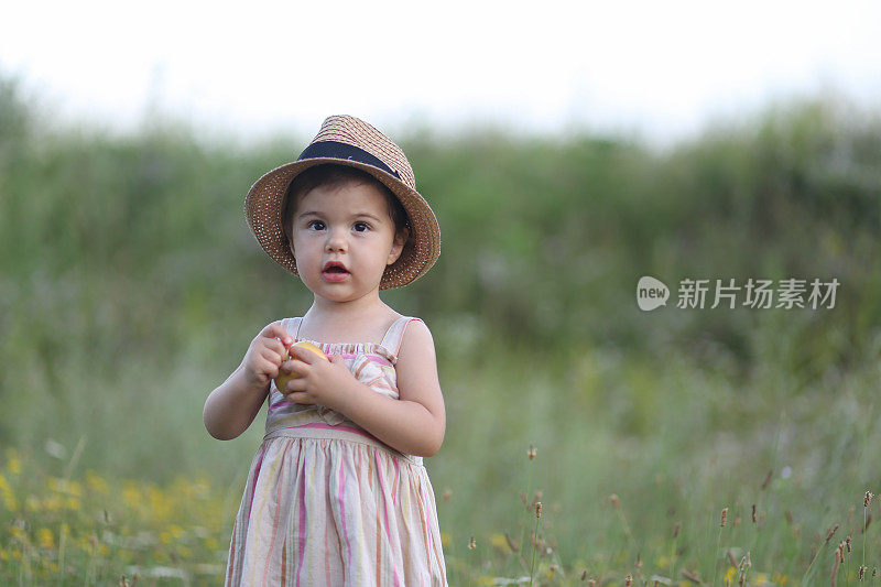 可爱的小女孩在户外吃苹果的照片