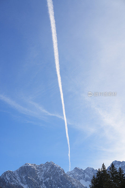 背景是雪山和蓝天，还有飞机的白色痕迹。
