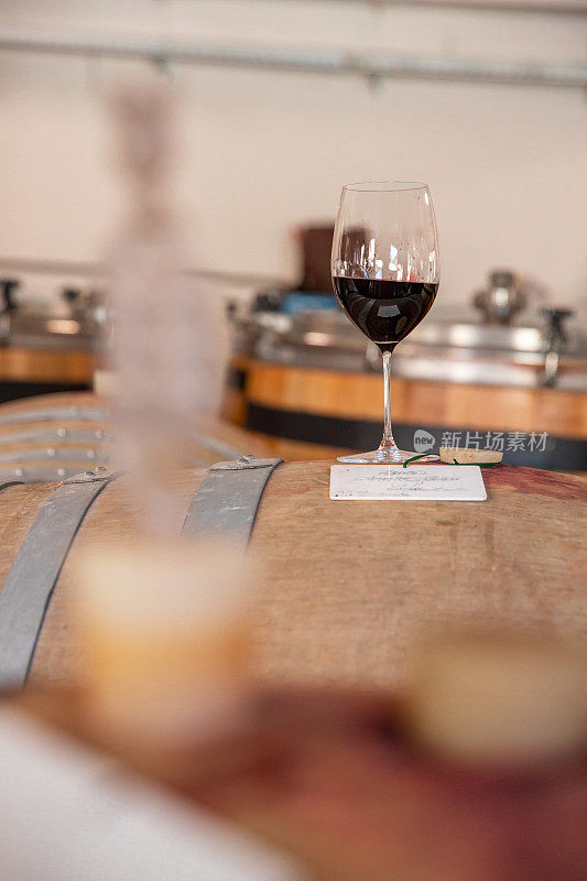 德国葡萄园酒窖用木桶上的酒杯品尝红葡萄酒