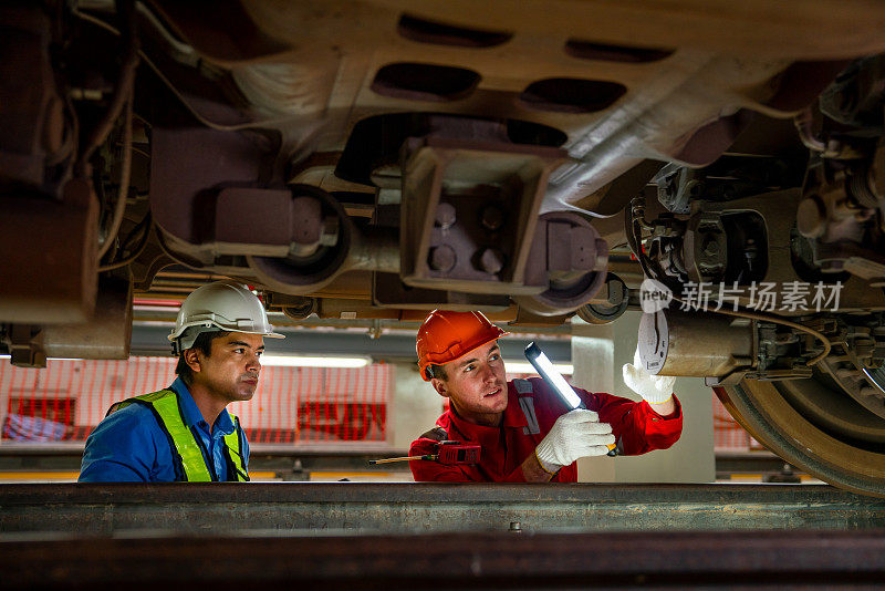 专业的工程师和技术工人在列车工厂的工作场所用灯管进行检查和维护。