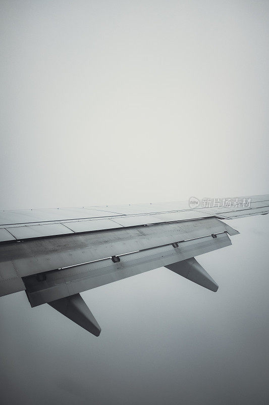 扇动翅膀飞过雾云乱流的飞机窗口景