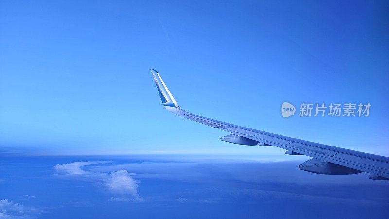 透过窗户看飞机在机翼飞行时与一个漂亮的蓝天云。