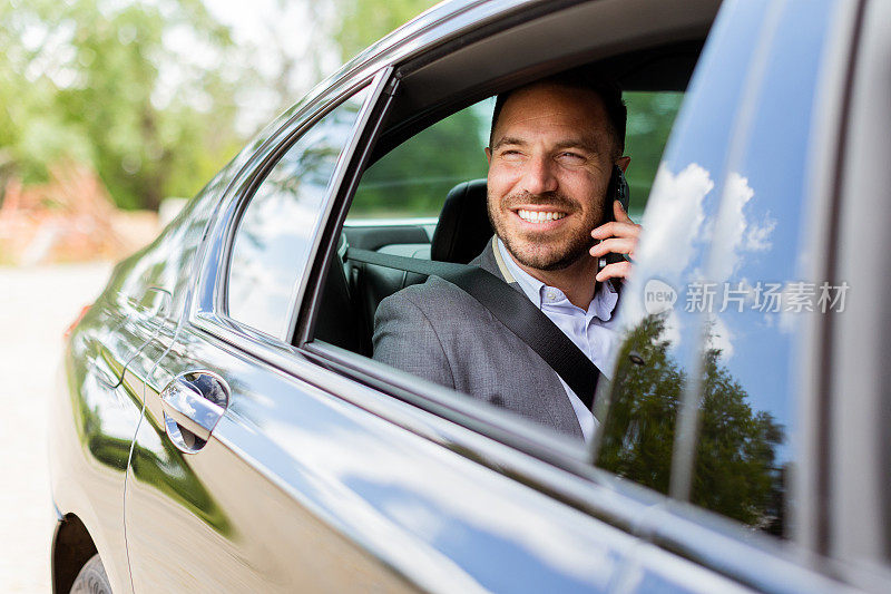 一个快乐的男人在大白天开车时一边打电话一边分享笑声
