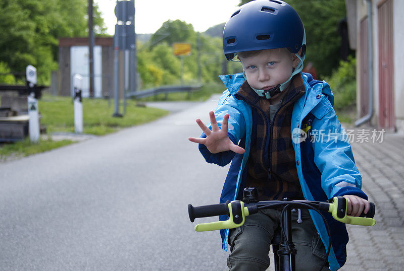 一个骑自行车的小男孩把手掌伸到前面，叫我停下来。