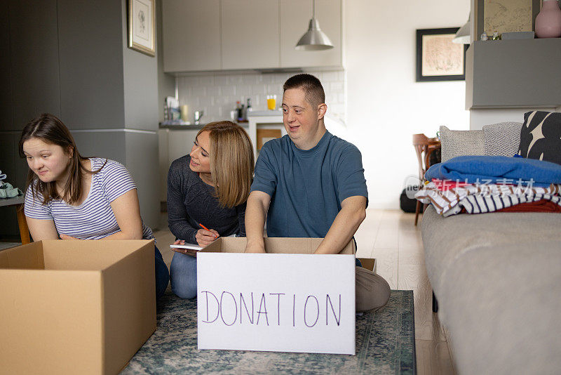 快乐的唐氏综合症患者在家里为慈善机构打包衣服。