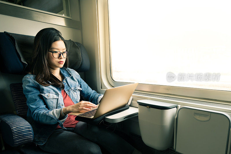 亚洲女性在火车上用笔记本电脑工作，商务旅行的概念