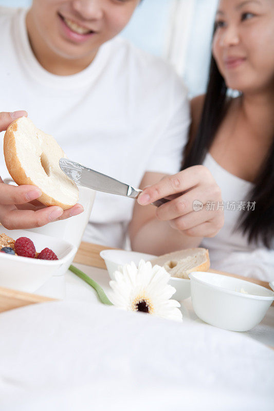 一对亚洲年轻夫妇在床上吃早餐