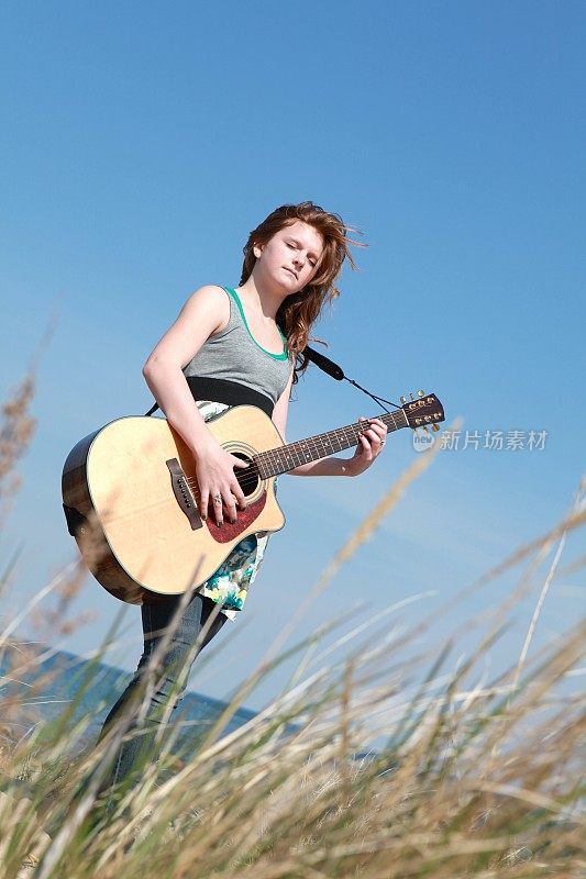 在海滩上弹吉他的女孩