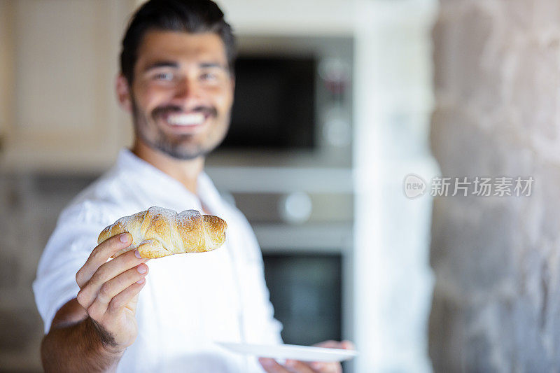 年轻的意大利人拿着牛角面包