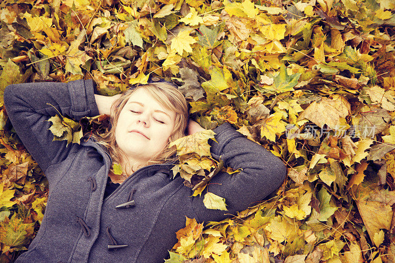 年轻女子在一堆落叶中休息