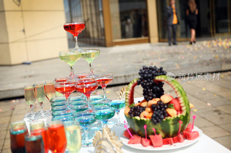 金字塔状的香槟酒杯和水果放在户外的桌子上。