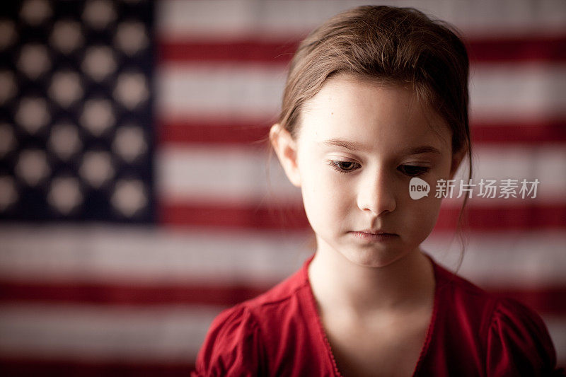 悲伤的年轻女孩在美国国旗前思考