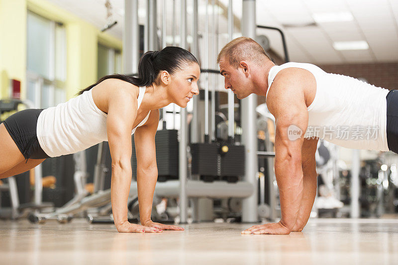 一对健身夫妇在健身房做俯卧撑