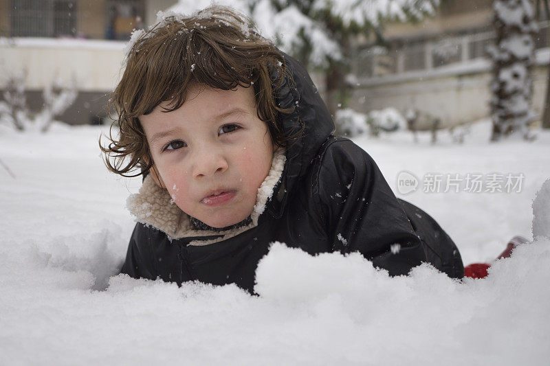 蹒跚学步的小男孩在玩雪