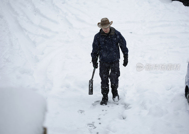 在加拿大下雪期间拿着铲子行走的男性青少年