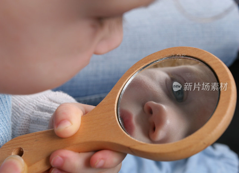 一个婴儿正在看自己在手镜中的倒影
