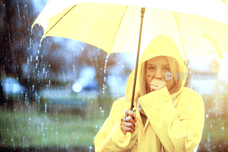 雨中穿着黄色雨衣的年轻女子