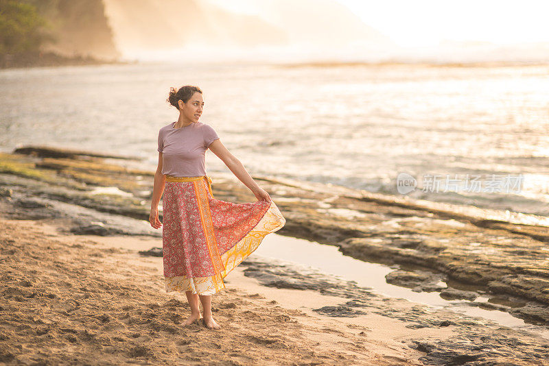 美丽的欧亚女人旋转在夏威夷海滩上日落接近