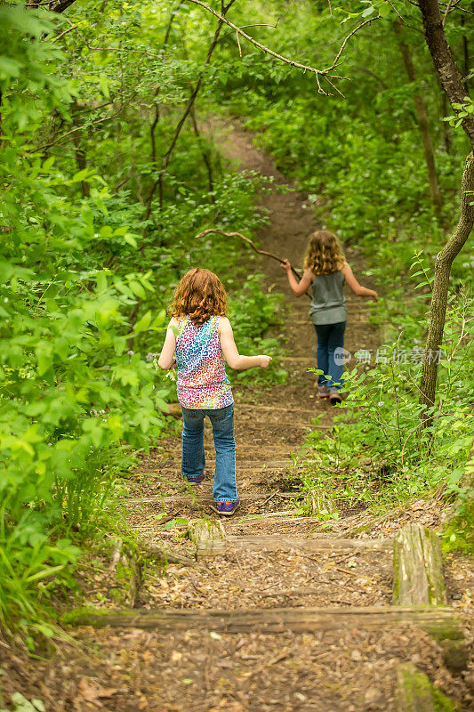 两个年轻女孩在穿越树林的楼梯小径上