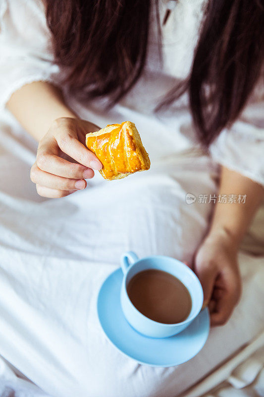 年轻女子在床上喝咖啡